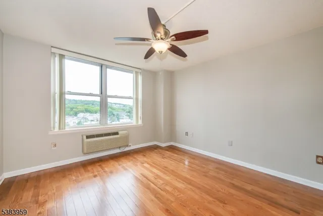 a view of empty room with wooden floor and fan