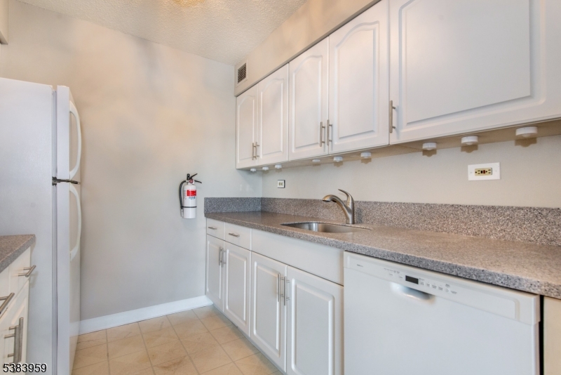300 Main Street, Unit 716 Little Falls, NJ 07424 - Photo 8 of 24 a kitchen with stainless steel appliances granite countertop white cabinets and a refrigerator