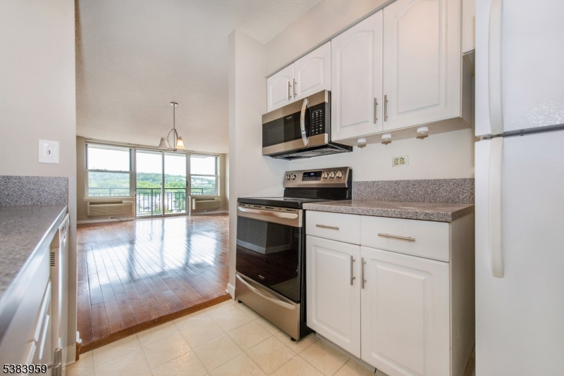 300 Main Street, Unit 716 Little Falls, NJ 07424 - Photo 10 of 24 a kitchen with stainless steel appliances granite countertop a stove a microwave and a white cabinets