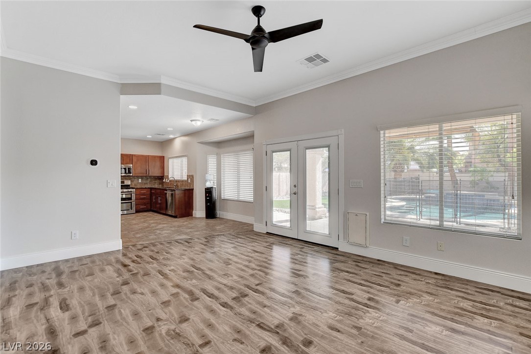 191 Verde Ridge Court Henderson, NV 89012 - Photo 8 of 36 Unfurnished living room with light wood-style flooring, crown molding, baseboards, french doors, and ceiling fan