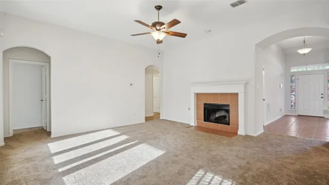 an empty room with a fireplace and a ceiling fan