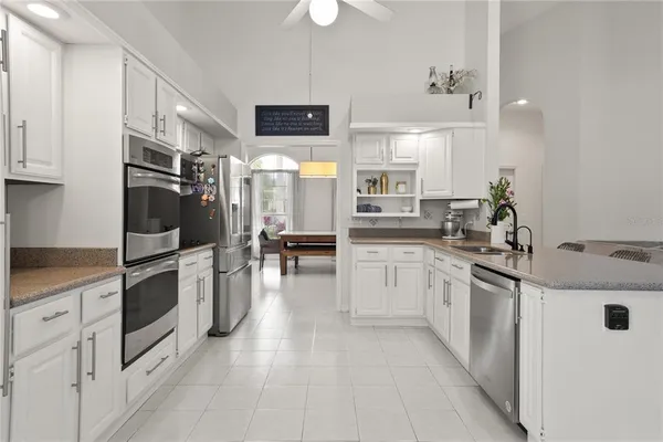 a kitchen with stainless steel appliances granite countertop a stove top oven a sink a window and white cabinets
