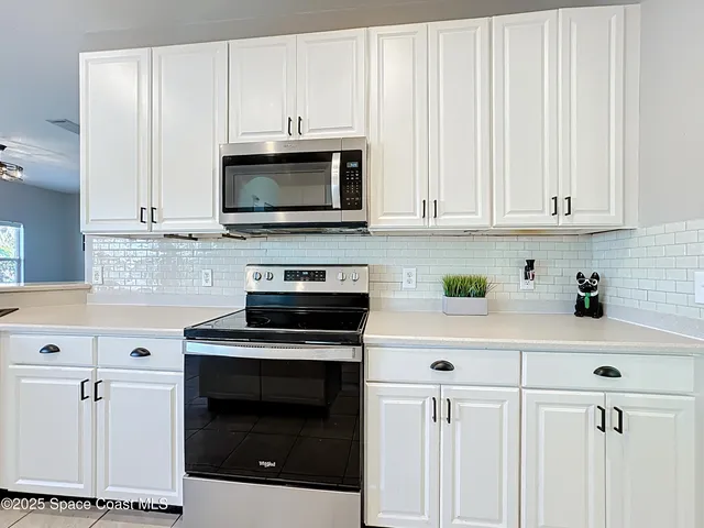a kitchen with granite countertop white cabinets white appliances with a sink and dishwasher