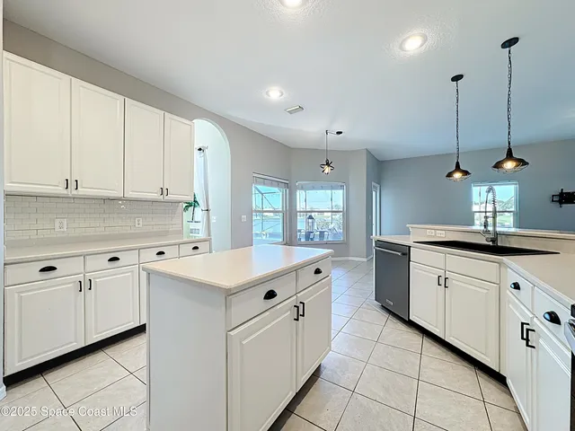 a view of a kitchen with kitchen island a sink wooden floor and a living room