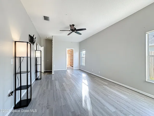 a view of empty room with wooden floor and ceiling fan