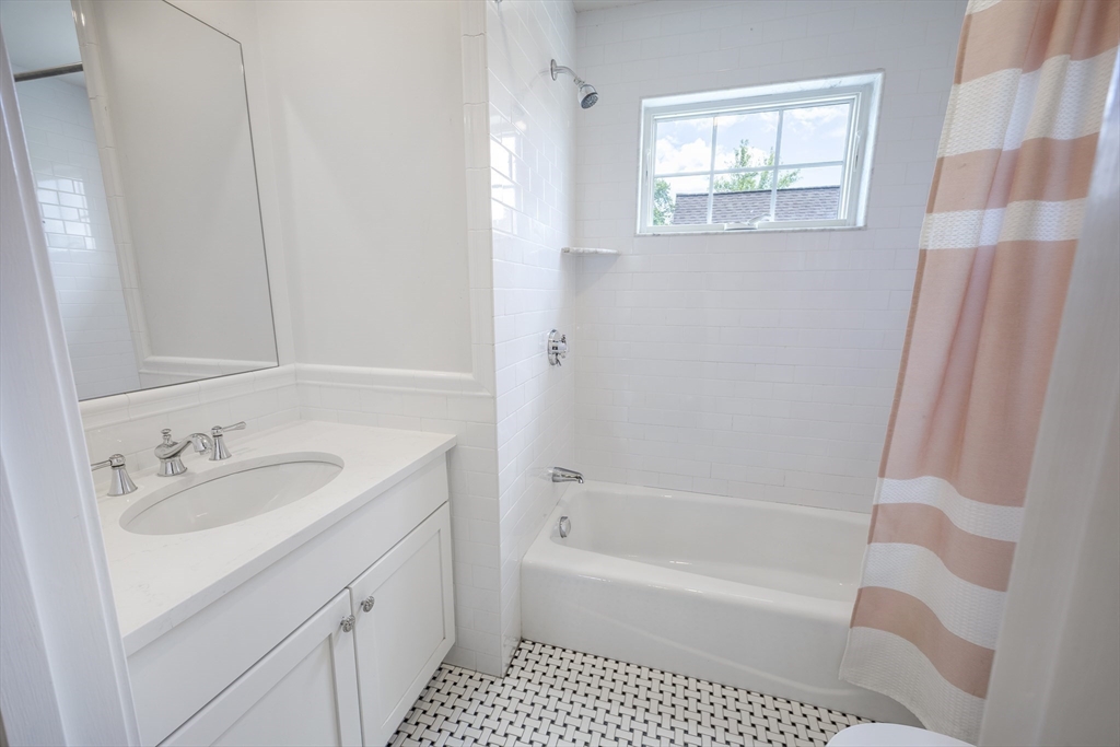 48 Spruce Street, Unit 1 Winchester, MA 01890 - Photo 17 of 29 a bathroom with a sink a mirror a bathtub and shower