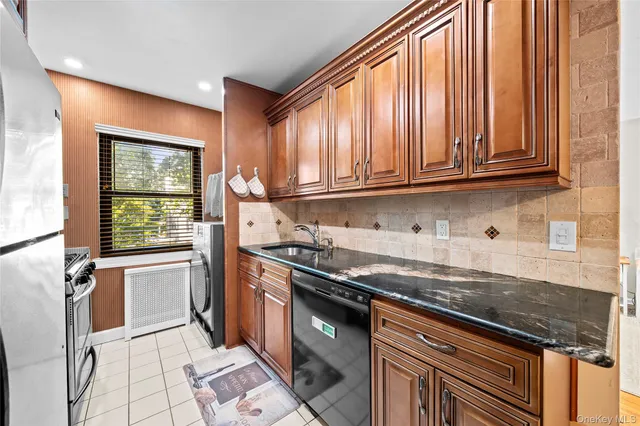 a kitchen with granite countertop stainless steel appliances a stove sink and cabinets