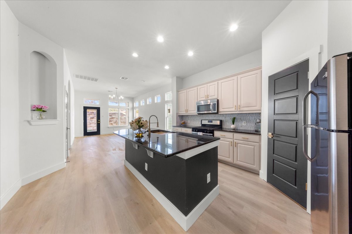 2408 Vintage Stave Road, Unit 101 Austin, TX 78748 - Photo 4 of 32 Kitchen featuring stainless steel appliances, recessed lighting, a kitchen island with sink, light wood-style flooring, and decorative backsplash