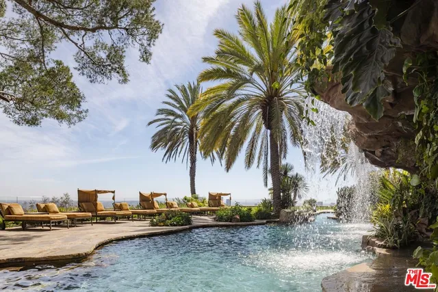 a small pool with lawn chairs under an umbrella