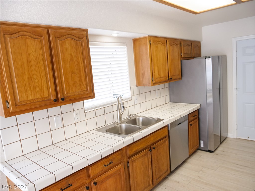 Classic wooden cabinetry pairs with tile countertops and modern stainless steel appliances