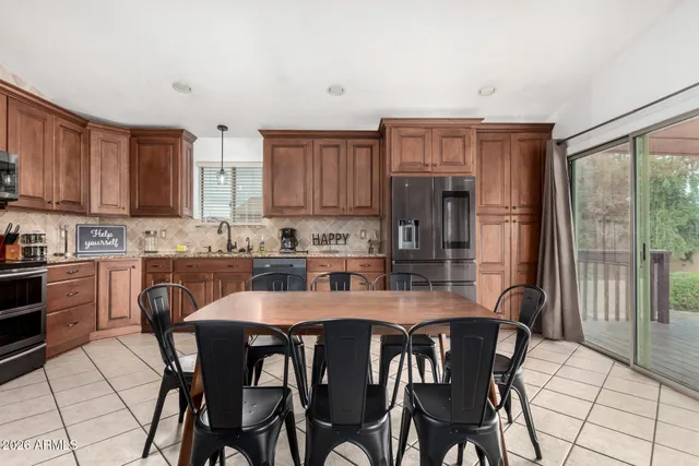 a kitchen with stainless steel appliances granite countertop a stove a refrigerator a kitchen island a table and chairs