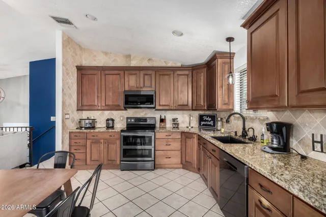 a kitchen with stainless steel appliances granite countertop a stove top oven a sink dishwasher and a microwave oven on the blue kitchen countertops