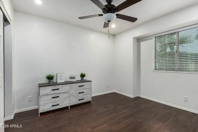 an empty room with a ceiling fan and wooden floor