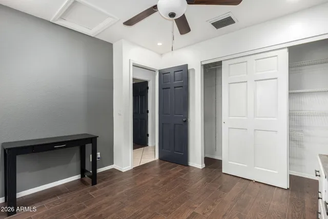 an empty room with wooden floor ceiling fan and windows
