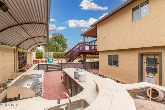 a view of a patio with couches table and chairs under an umbrella with a barbeque