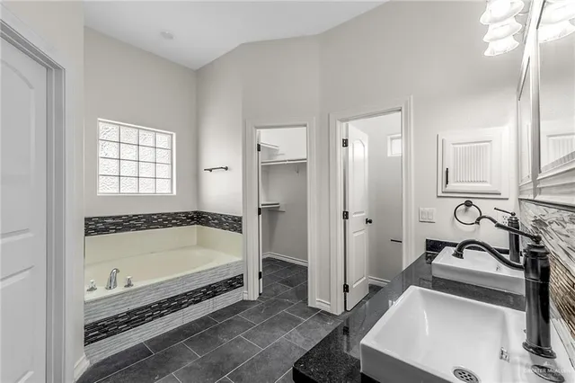 a bathroom with a tub a sink a mirror and a shower