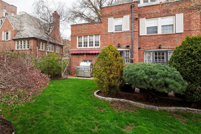 a view of a house with brick walls and a yard with plants