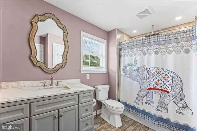 a bathroom with a toilet sink vanity tub and mirror