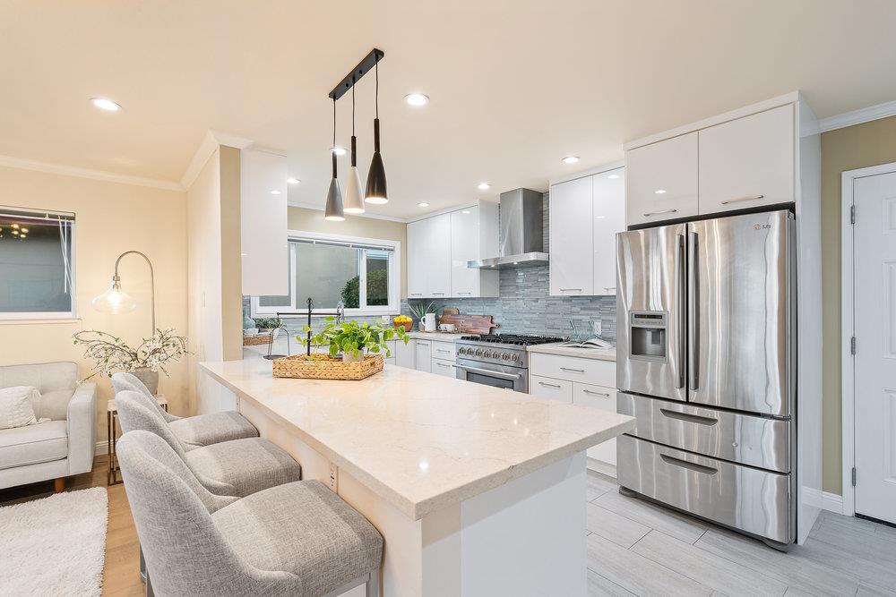 708 Morningside Drive Millbrae, CA 94030 - Photo 11 of 36 a kitchen with stainless steel appliances kitchen island granite countertop a refrigerator a sink dishwasher a stove and a dining table with wooden floor