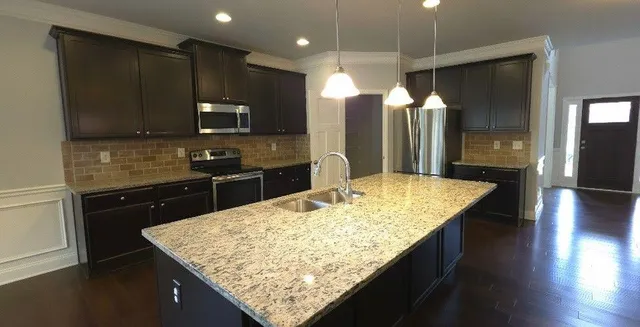 a kitchen with kitchen island granite countertop wooden cabinets and a refrigerator