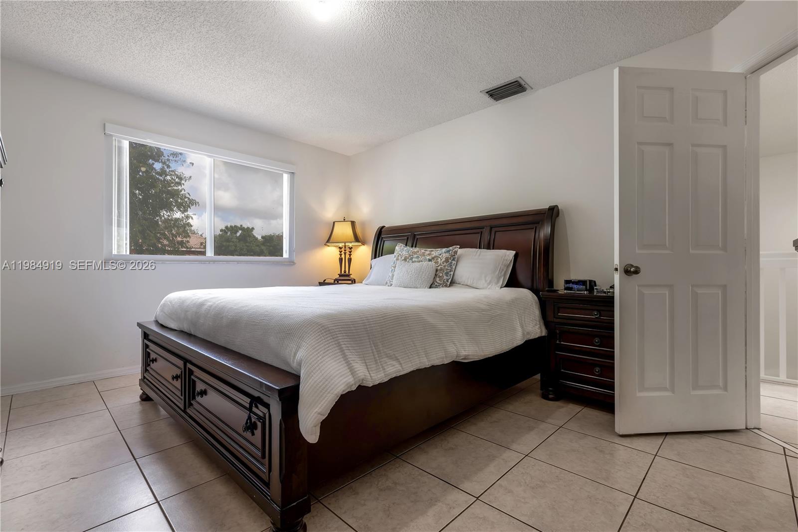 16323 Southwest 97th Street Miami, FL 33196 - Photo 18 of 44 a bed sitting in a bedroom next to a window