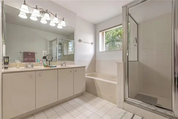 a bathroom with a double vanity sink a mirror a bathtub and next to a window