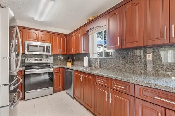a kitchen with stainless steel appliances granite countertop a refrigerator sink and cabinets
