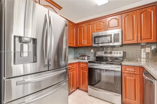 a kitchen with stainless steel appliances granite countertop a refrigerator stove and sink