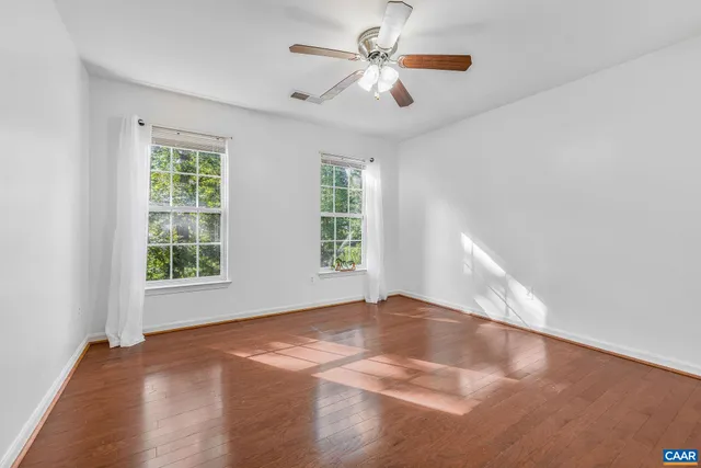 a view of an empty room with window and chandelier fan