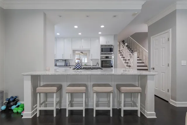 a kitchen with stainless steel appliances granite countertop a table chairs sink and cabinets