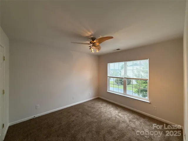 an empty room with a ceiling fan and window