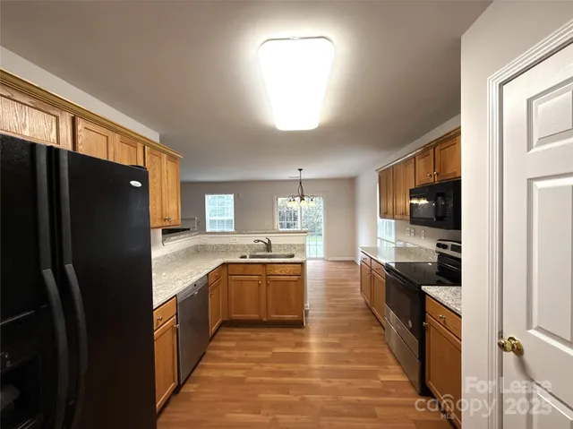 a large kitchen with stainless steel appliances granite countertop a refrigerator and a stove