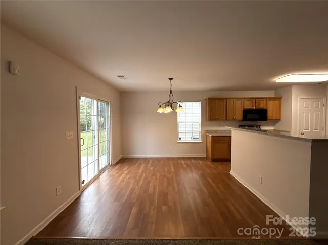 a view of kitchen with microwave a stove and wooden floor