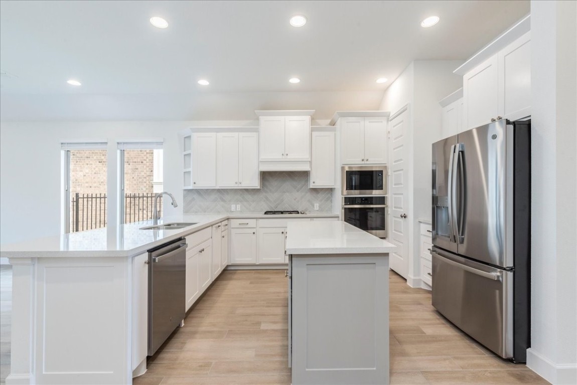 164 Kimble Creek Loop Kyle, TX 78640 - Photo 6 of 35 a white kitchen with granite countertop a refrigerator oven a sink and dishwasher with wooden floor