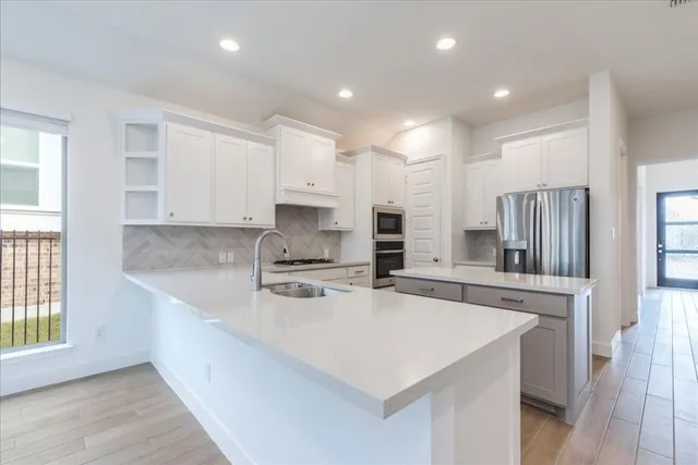 a kitchen with stainless steel appliances a sink a stove a refrigerator and cabinets