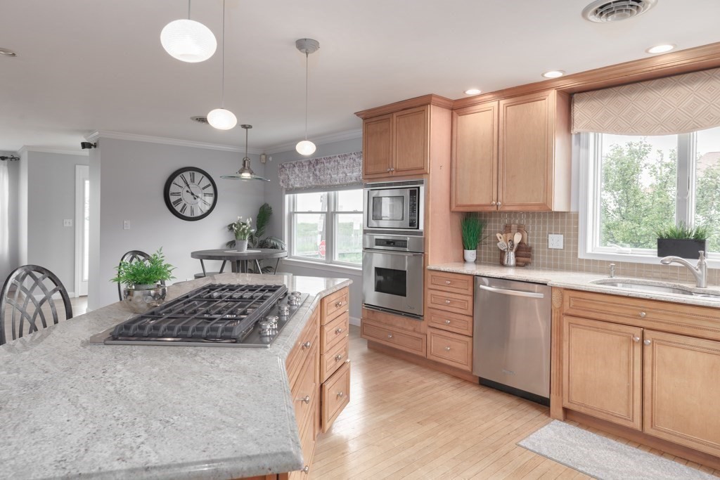 175 Rice Avenue Revere, MA 02151 - Photo 8 of 30 a kitchen with stainless steel appliances granite countertop a sink a stove a oven a dining table and chairs with wooden floor