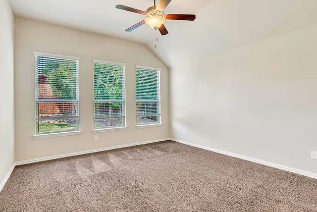 an empty room with a ceiling fan and window