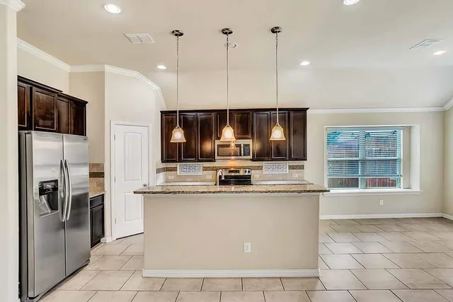 a kitchen with stainless steel appliances granite countertop a sink a stove and a refrigerator