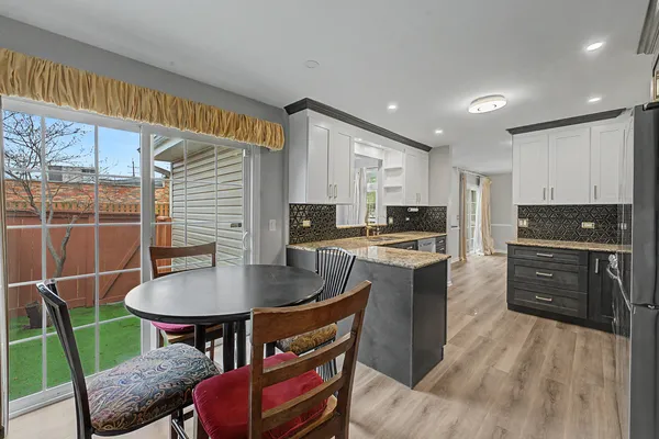 a kitchen with stainless steel appliances granite countertop a stove a refrigerator a kitchen island a table and chairs