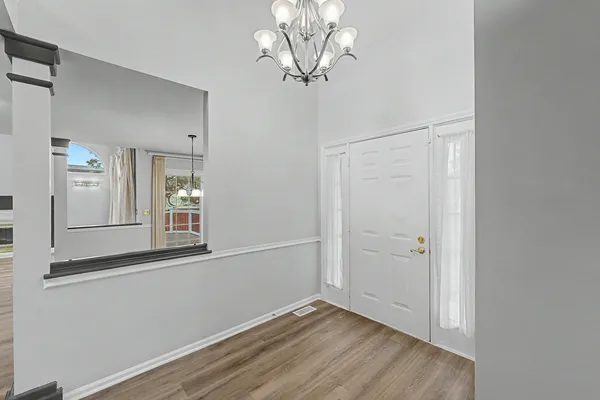 a view of a room with wooden floor and a chandelier