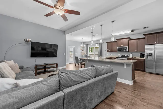 a living room with furniture kitchen view and a flat screen tv