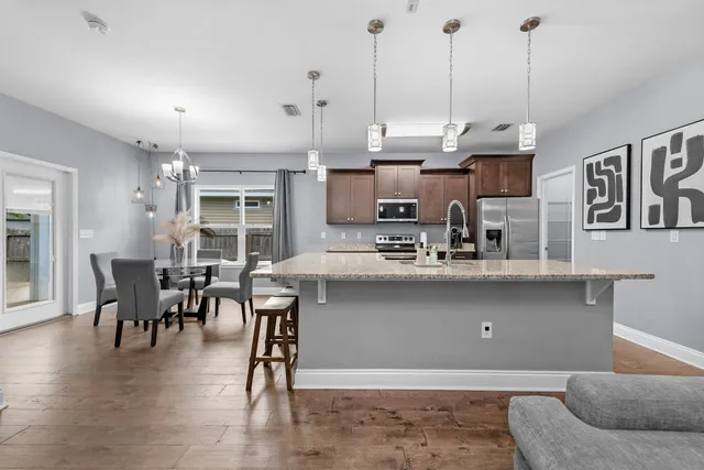 a kitchen with stainless steel appliances granite countertop a sink a stove and a wooden floors