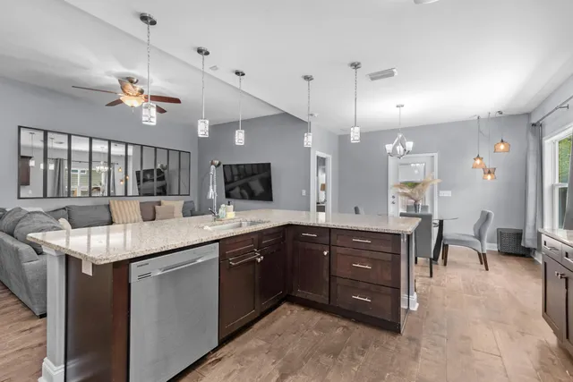 a kitchen with a sink a counter space appliances and a view of living room