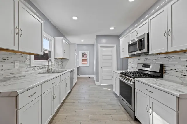 a large kitchen with stainless steel appliances granite countertop a stove sink and cabinets