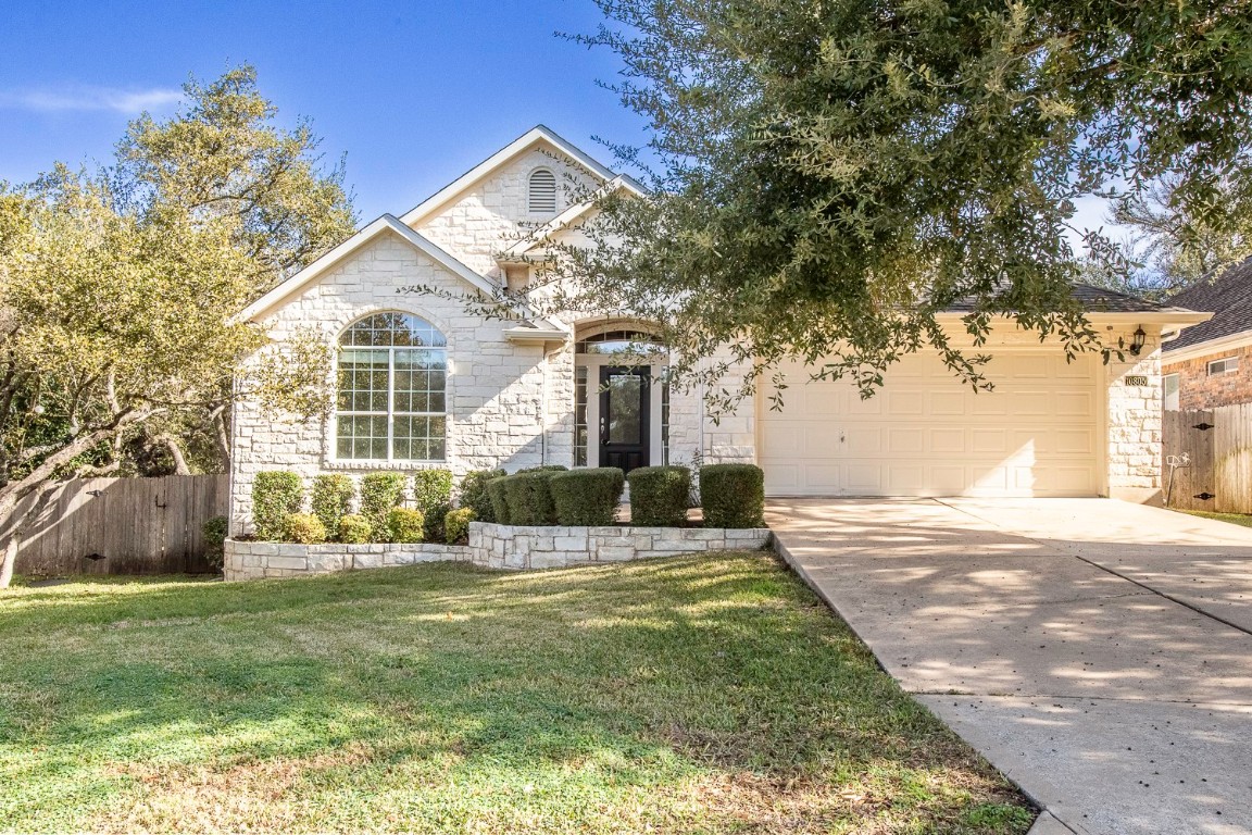 View of front of house featuring stone siding, driveway, and an attached garage