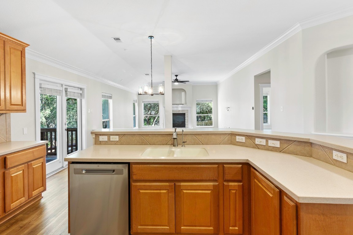 10805 Ariock Lane Austin, TX 78739 - Photo 13 of 40 Kitchen with brown cabinets, dishwasher, ornamental molding, pendant lighting, and ceiling fan