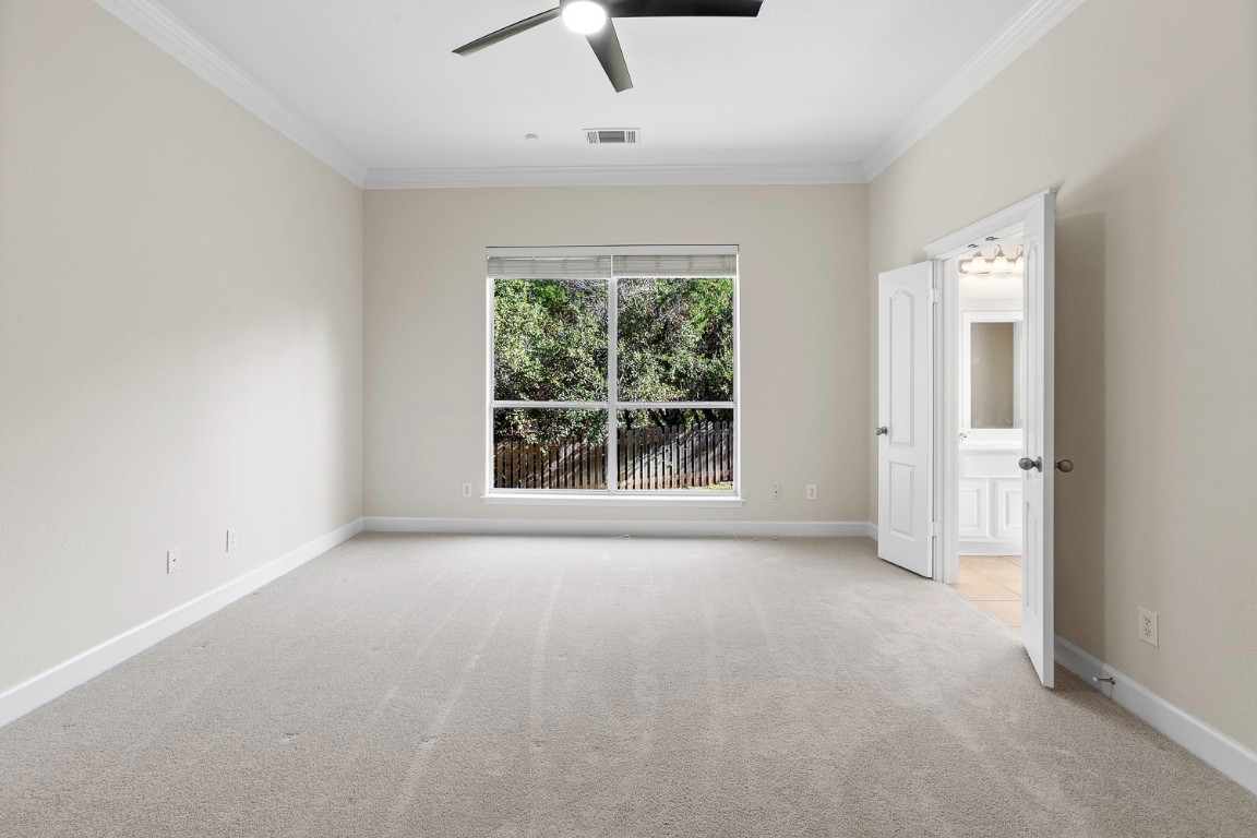 10805 Ariock Lane Austin, TX 78739 - Photo 15 of 40 Unfurnished bedroom featuring light colored carpet, a ceiling fan, ornamental molding, and connected bathroom