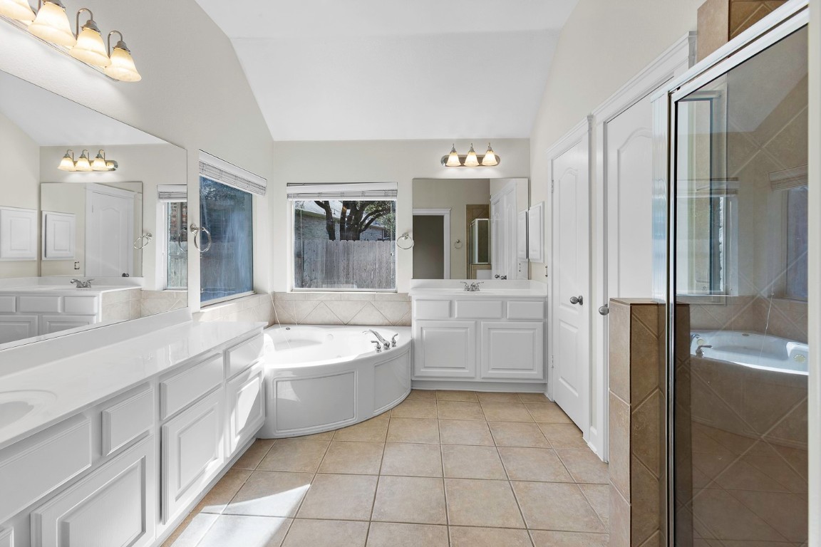10805 Ariock Lane Austin, TX 78739 - Photo 18 of 40 Bathroom with a garden tub, light tile patterned floors, vaulted ceiling, two vanities, and a shower stall