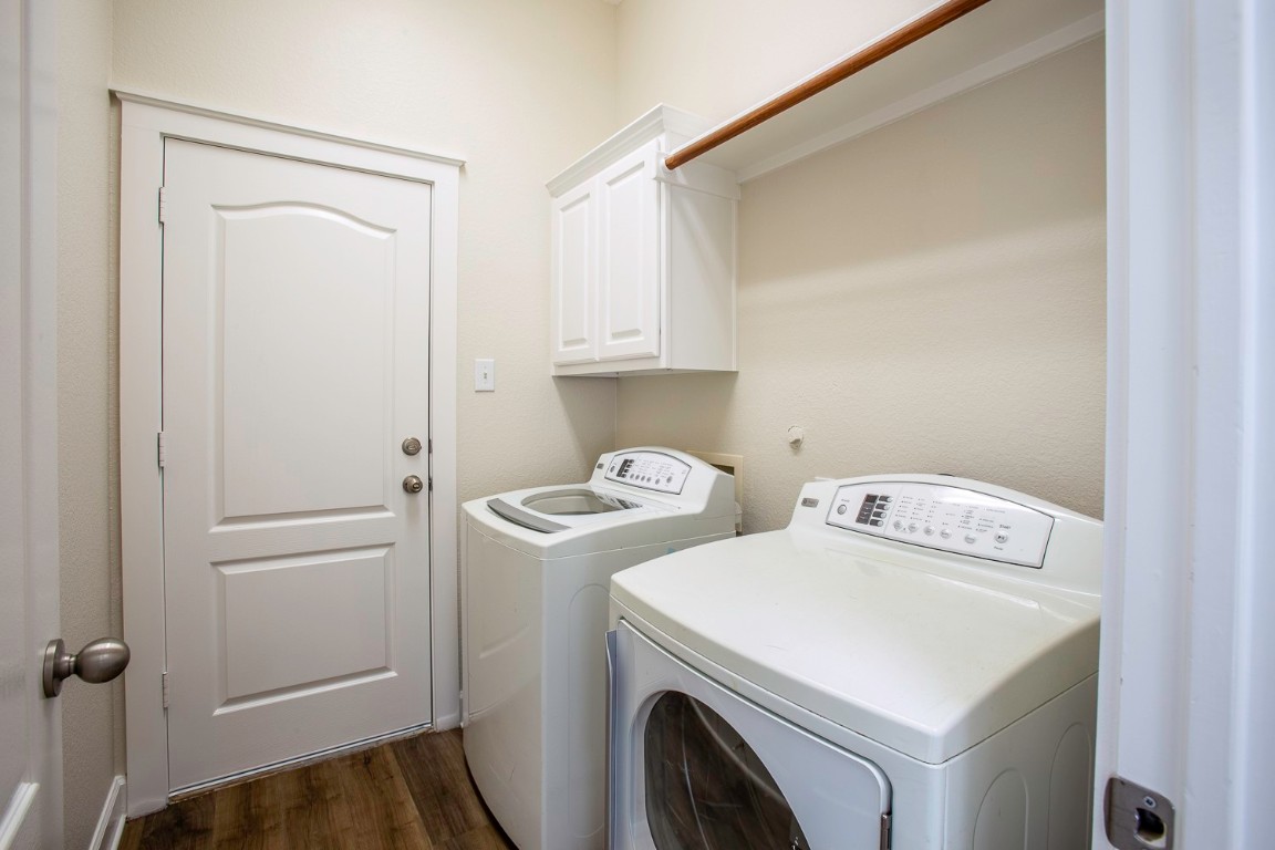 10805 Ariock Lane Austin, TX 78739 - Photo 31 of 40 Laundry area featuring dark wood-style floors, washing machine and clothes dryer, and cabinet space