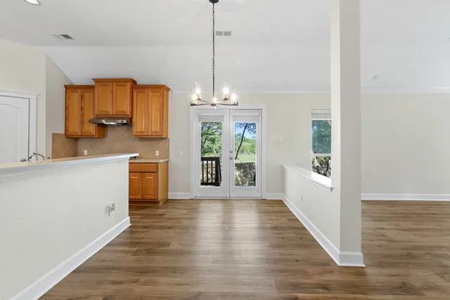 a kitchen with stainless steel appliances granite countertop a refrigerator a sink dishwasher a stove and white countertops with wooden floor